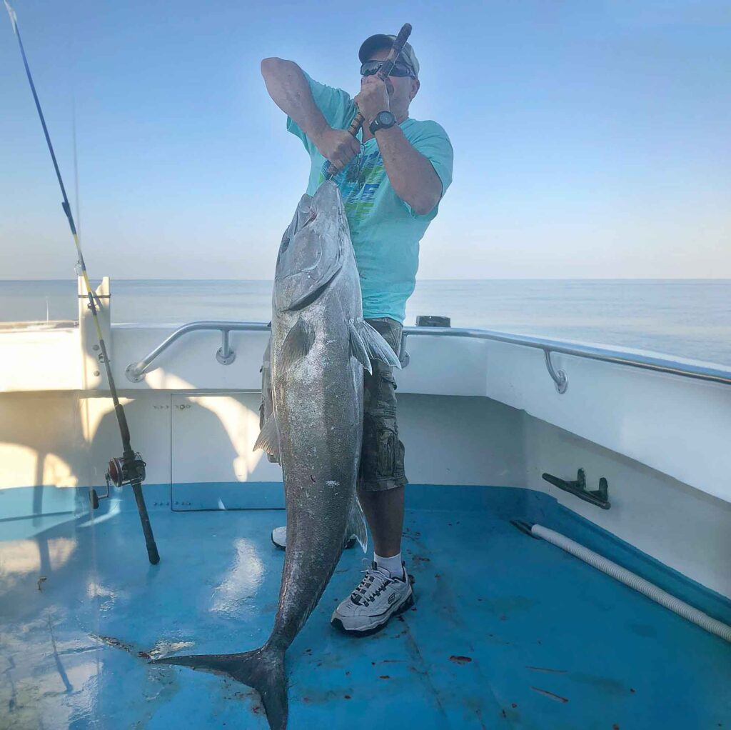 A man holding his 90-pound amberjack caught off Destin Florida's Finest Kind Charter Boat.