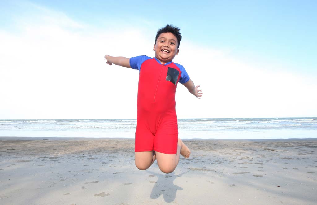 Exuberant boy jumping on the beach.