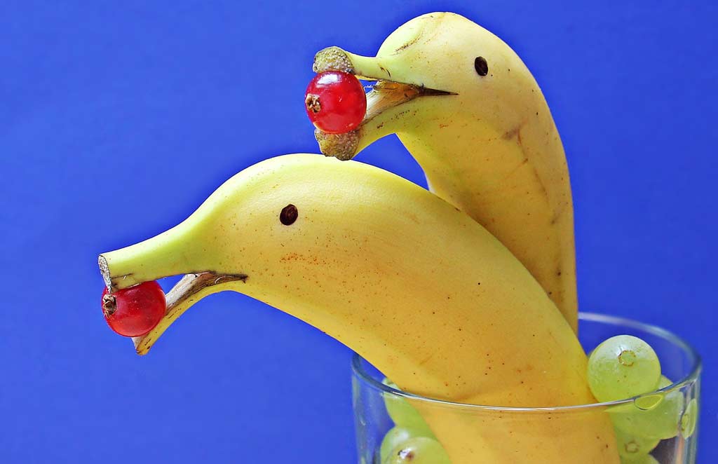 Bananas that look like dolphins with grapes.